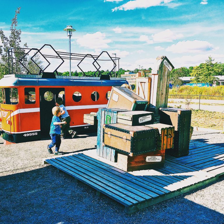 Barn som leker i en park med objekt som föreställer tåg.